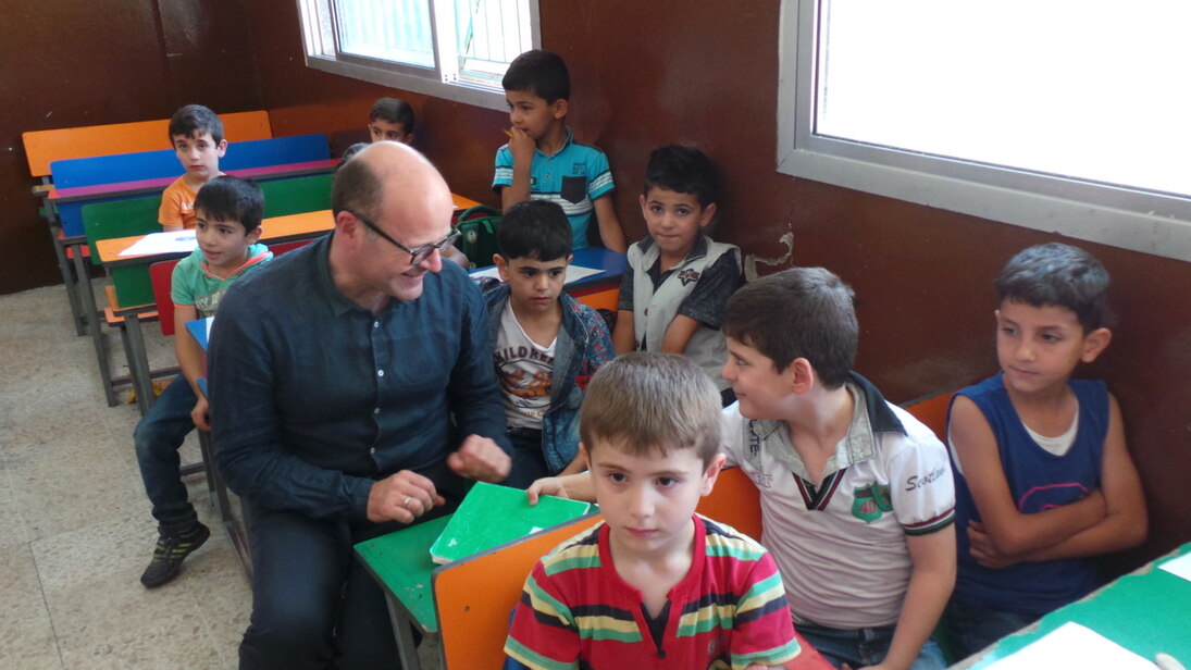 Ein Mann sitzt mit Kindern in einem Klassenraum