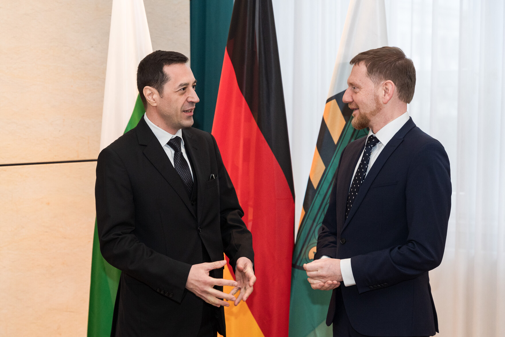 Zwei Männer stehen vor Flaggen