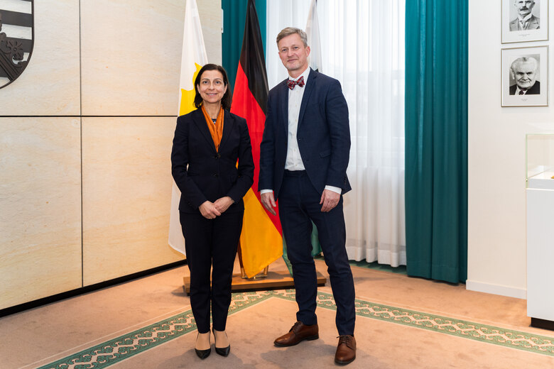 Eine Frau und ein Mann stehen vor einer Fahnengalerie