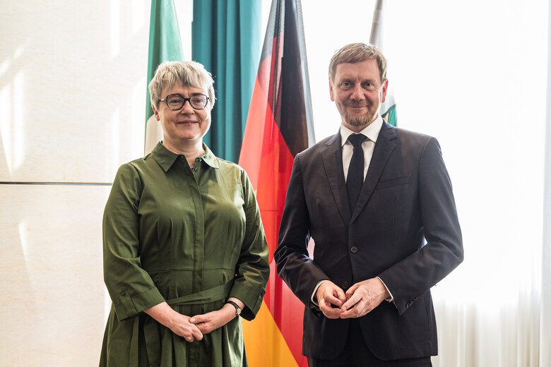 Eine Frau und ein Mann stehen vor einer Fahnengalerie