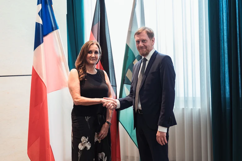 Eine Frau und ein Mann stehen vor einer Fahnengalerie.