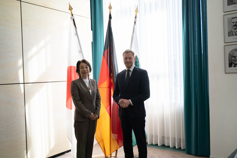 Eine Frau und ein Mann stehen vor einer Fahnengalerie