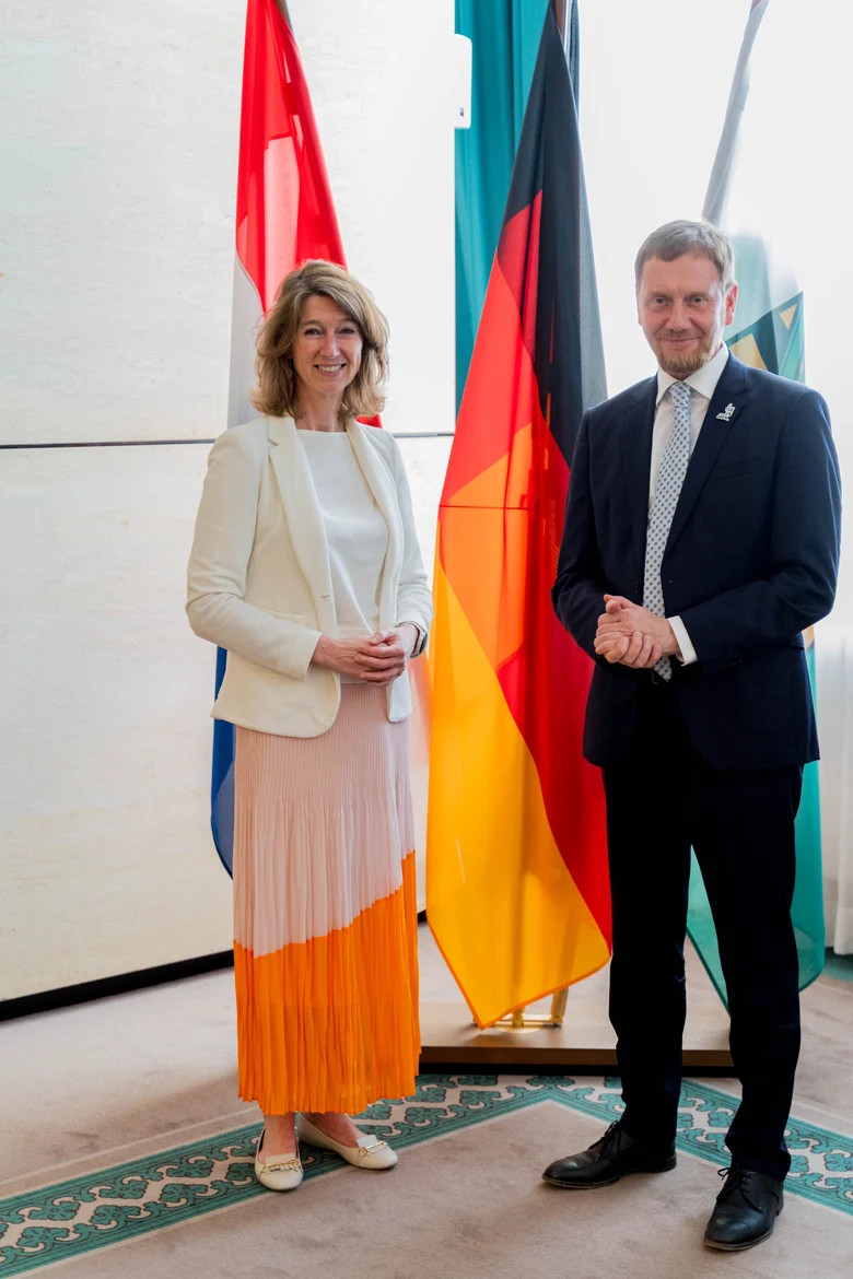 Eine Frau und ein Mann stehen vor einer Fahnengalerie.