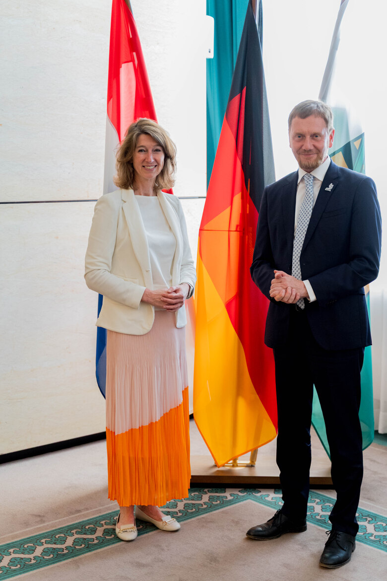 Eine Frau und ein Mann stehen vor einer Fahnengalerie.