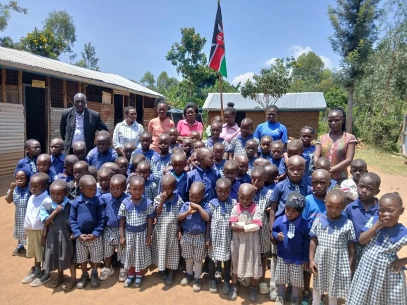 Gruppenfoto von Schulkindern und Lehrkräften vor einem Gebäude
