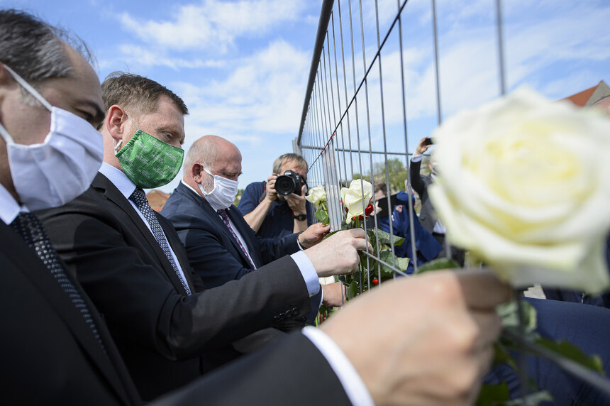Das Bild zeigt Ministerpräsident Michael Kretschmer und Görlitz Oberbürgermeister Octavian Ursu beim Befestigen weiße Rosen am Grenzzaun auf der Brücke zu Polen. 