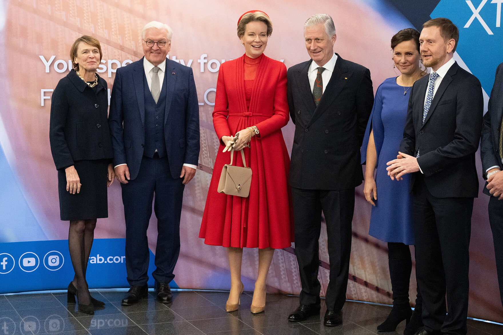 Männer und Frauen stehen vor einer Pressewand.