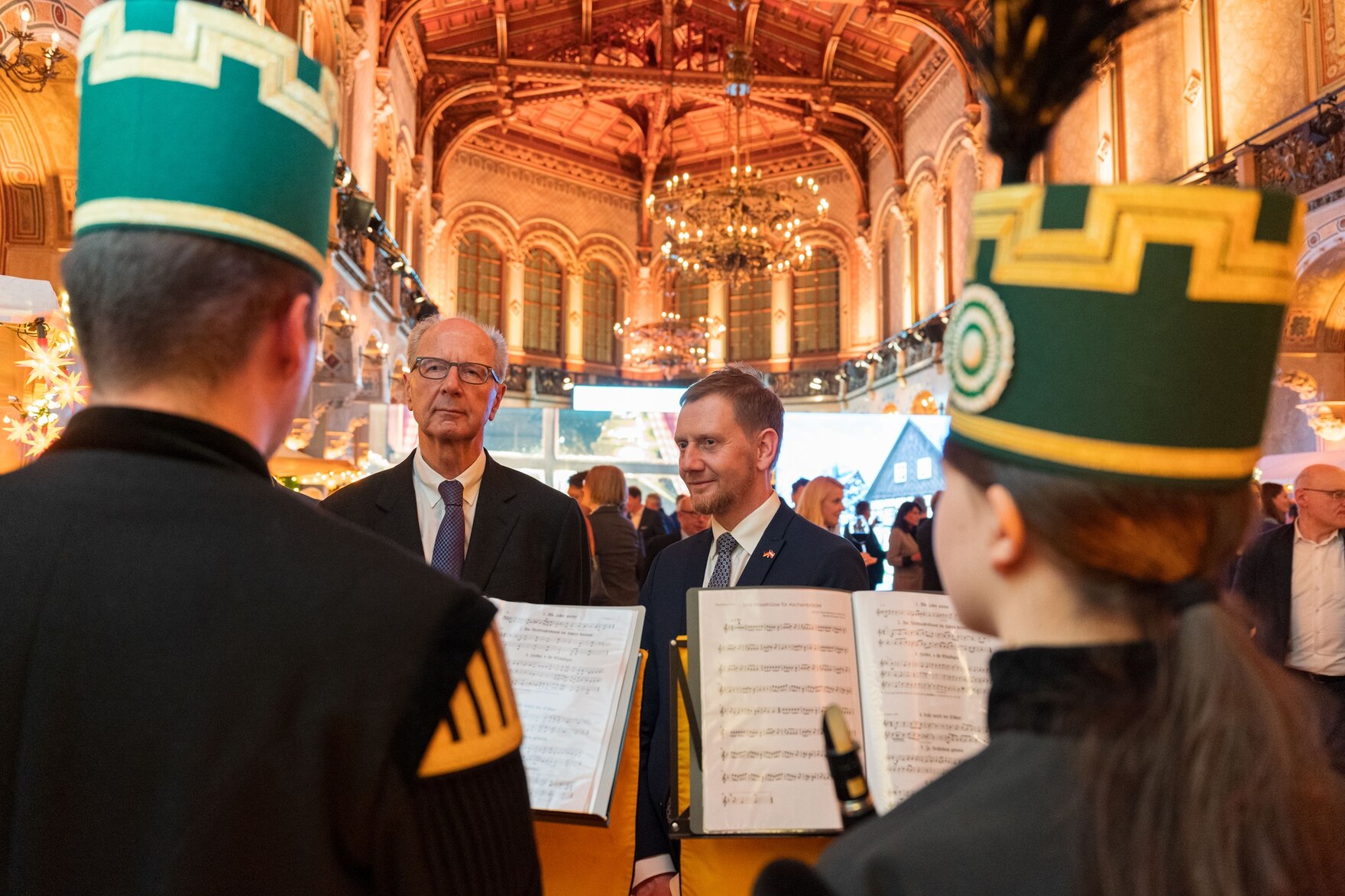 Zwei Männer stehen vor einer Gruppe Musikanten